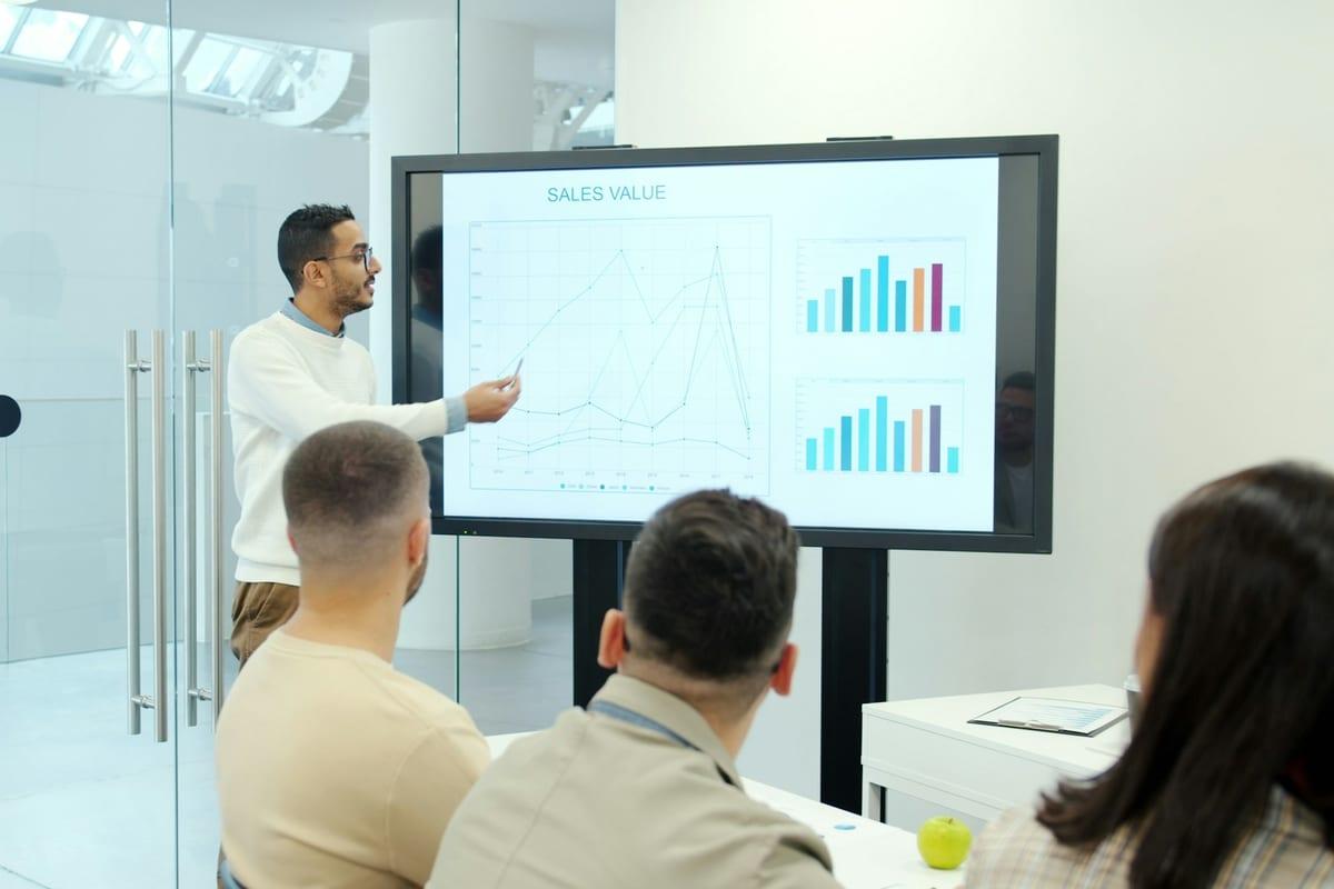A consultant presenting financial charts on screen to colleagues