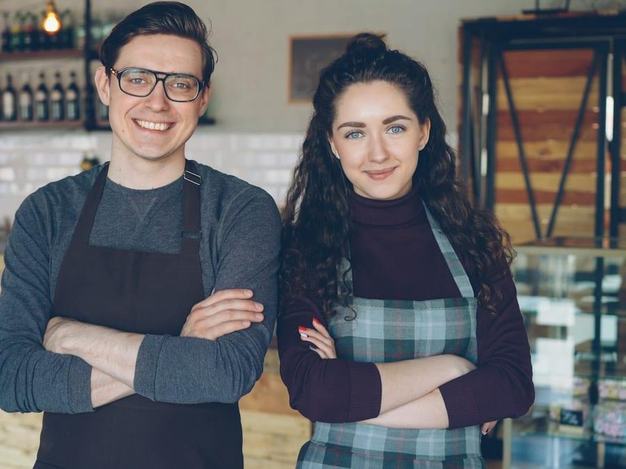 Two owners standing together behind the counter of their café